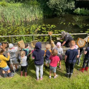 Ray Jackson MBE and a group of children enjoying pond dipping